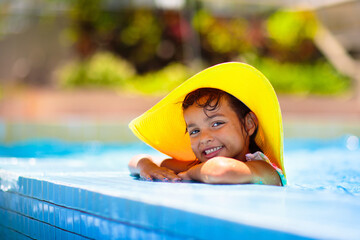 Child in swimming pool on ring toy. Kids swim.