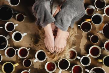 Fototapeta na wymiar Lots of cups of coffee and a tired woman. Deadline, overtime concept. Need for wakefulness.