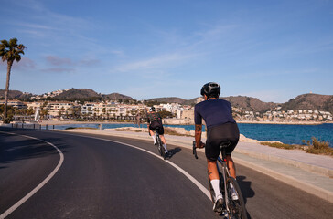 Professional cyclists training on road bicycles with a sea view in Spain.Sportsmen training hard on bicycle outdoors.Sports motivation.
