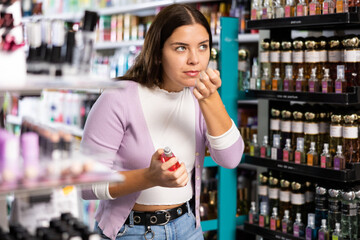 Young girl smelling perfume tester in cosmetics store