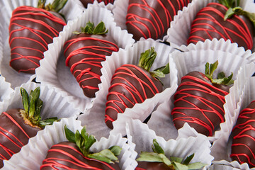Wall of multiple dark chocolate-covered strawberries with green tuffs and Valentine’s day drizzle