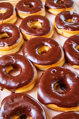 Half glazed yeast donuts with chocolate frosting on white tray background