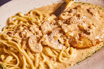 Chicken Marsala with red wine pasta sauce creamy Italian food dish with knife and white plate