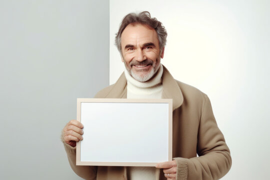 Portrait of smiling senior man holding blank board and looking at camera