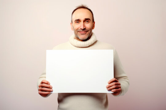 Portrait of a middle-aged man in a sweater holding a white sheet of paper