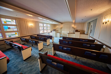 Blue carpeted church with wooden pews, red cushions, bibles, psalms, religious book texts chapel