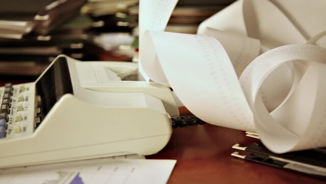 Time lapse of a man's hand using a calculator on a cluttered office desk.