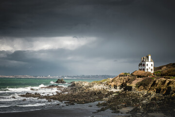 Fototapeta na wymiar Isolated white house on the rocky coast of Brittany in France in a bad weather sky