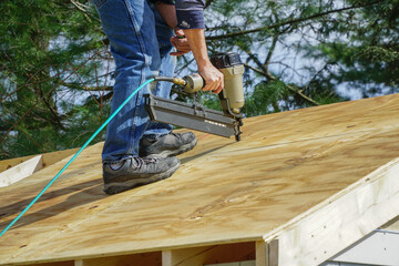 handyman using nail gun to install shingle to repair roof