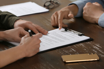 Notary working with couple at wooden table, closeup