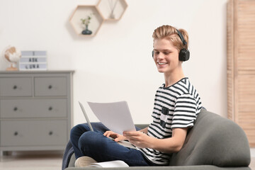 Online learning. Smiling teenage boy with laptop looking on essay at home