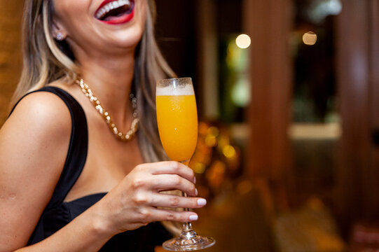 Blonde Woman Holding Mimosa Glass And Smiling