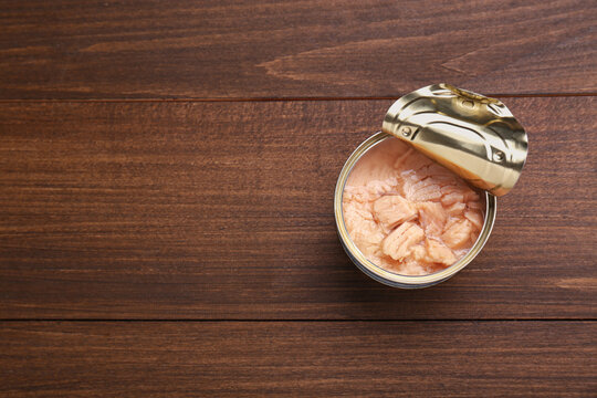 Can of conserved tuna on wooden table, top view. Space for text