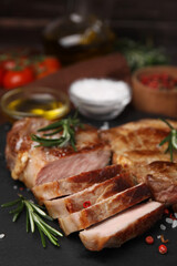Pieces of delicious fried meat with rosemary and spices on slate plate, closeup