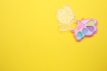 Decorative cosmetics for kids. Eye shadow palette on yellow background, top view. Space for text