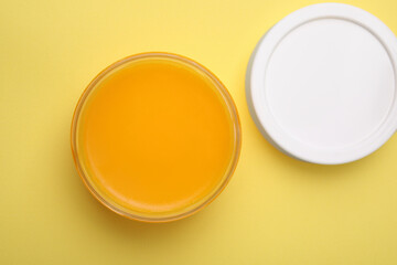 Open jar of petrolatum on yellow background, top view