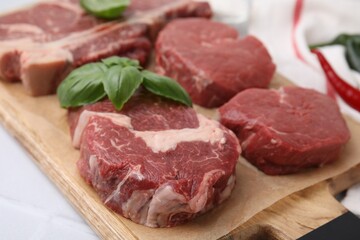 Cut fresh beef meat with basil leaves on wooden board, closeup