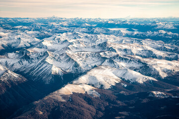 View of the snow-covered Andes Mountains through the window of an airplane at sunrise