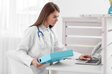 Female doctor working with laptop at reception in clinic