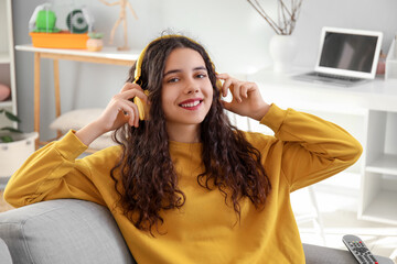 Teenage girl in headphones listening to music at home
