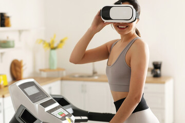 Sporty young woman in VR glasses training on treadmill at kitchen