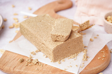 Board with tasty halva and peanuts on white background