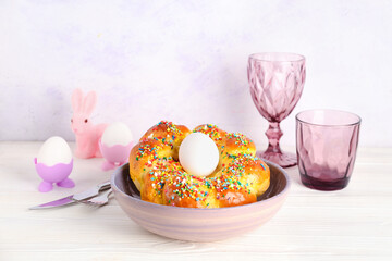 Bowl with tasty Italian Easter bread, eggs and glasses on light wooden table