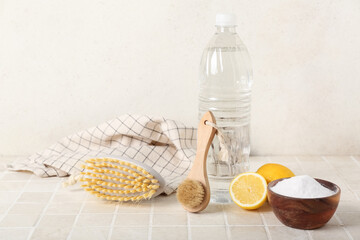 Bowl of baking soda, vinegar, cleaning brushes, lemons and napkin on light tile table