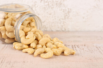 Jar with tasty cashew nuts on light background