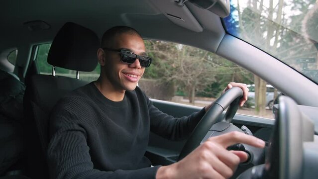 Smiling young black guy using a GPS navigation system before driving the car. High quality 4k footage