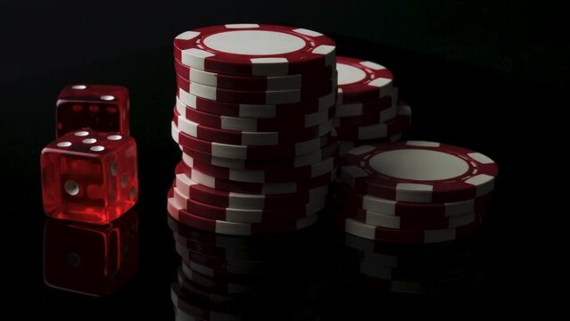 4K Video of Spinning Red Dice and Poker Chips on a moody black background Concept for Winning Betting Strategy, Las Vegas Fun, Luck in Casino Gaming and Dark Side of Gambling