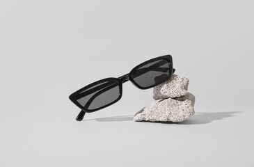 Stones with stylish sunglasses on grey background