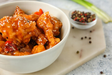 Tasty sweet and sour chicken in bowl with spices on light background, closeup