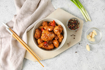 Tasty sweet and sour chicken in bowl with spices on light background