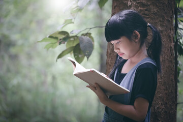Fototapeta premium Cute smile asian little girl reading book in garden