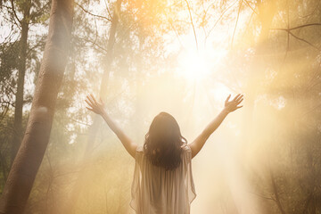 Fototapeta na wymiar a woman standing in the middle of the forest with arms outstretched in the bright morning sunray