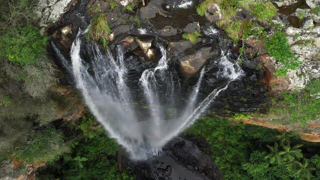 Aerial top down view over Purling Brook falls with a fly out to reveal lower pool and surrounds. Springbrook National park, Gold Coast hinterland