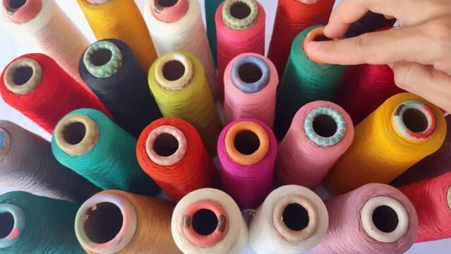 View of a man's hand picking up a spool among colorful treads 