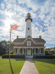 Obraz premium sunny day at the lighthouse in St. Simons, GA with an American flag blowing in the wind