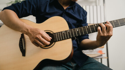 Obraz na płótnie Canvas Young joyful asian handsome man playing guitar at home.