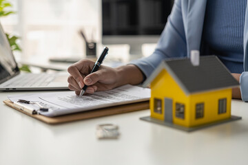 Home sales office, female employees inspect the lease agreement and small yellow house to prepare to meet customers to sign the lease agreement. Real Estate Rental Ideas