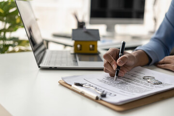 Fototapeta premium Home sales office, female employees inspect the lease agreement and small yellow house to prepare to meet customers to sign the lease agreement. Real Estate Rental Ideas