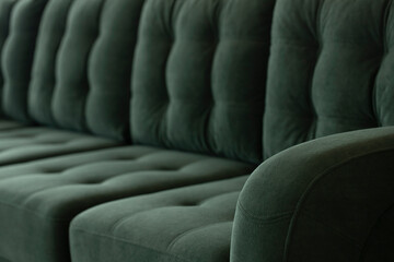 Quilted vintage sofa background in emerald velour fabric. Stitched elegant vintage upholstered furniture with a blurred background. Lateral part of a sofa with the stitched elbow. - obrazy, fototapety, plakaty