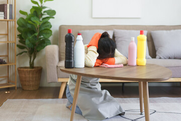 Maid exhausted and sleeping to resting on the table with cleansing bottles after cleaning in home