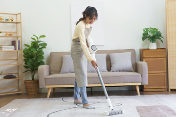 Maid using cordless vacuum cleaner to vacuuming and cleaning the dust on the carpet in home - obrazy, fototapety, plakaty