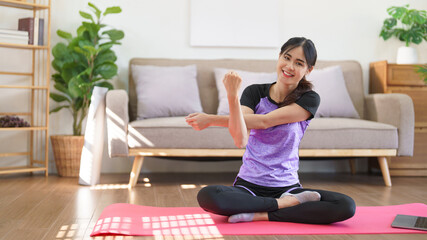 Sporty woman watching yoga training online and doing stretching arms to exercise for yoga at home