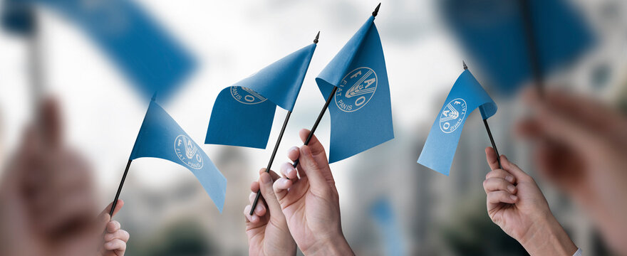A group of people holding small flags of the Food and agriculture organization in their hands
