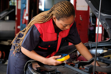 One Black female professional automotive mechanical worker checks an EV car battery and hybrid...