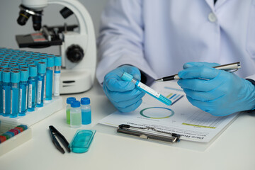 Male scientist using scientific test tubes with data recording of chemicals or drugs tested and examined by microscope in science laboratory for medicine biotechnology biology.