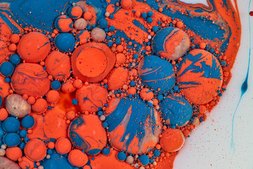 Bubbles popping in acrylic pouring of oil and blue gold orange and white paints in abstract background asset